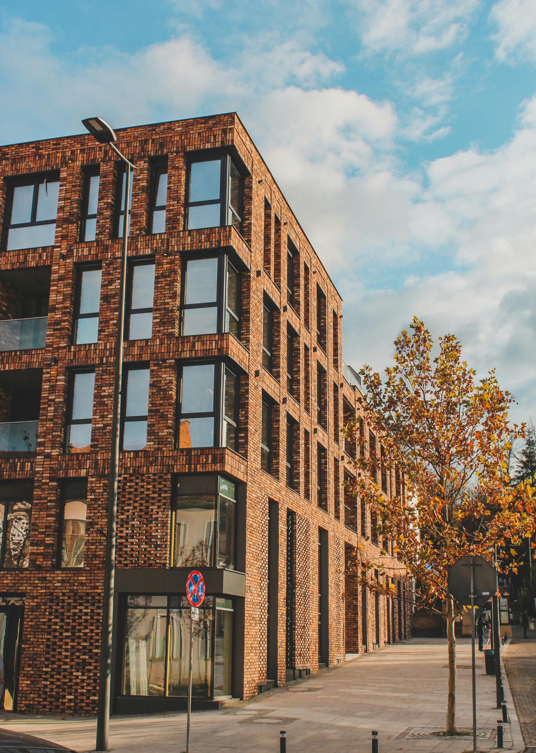 Contemporary brick building with glass windows in a sunny urban setting.